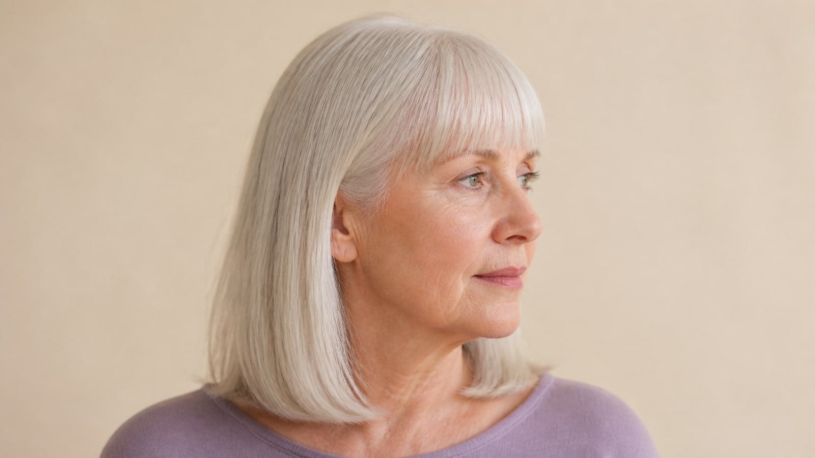 Profile view of straight silver shoulder-length hair with a full blunt fringe and clear temple connection