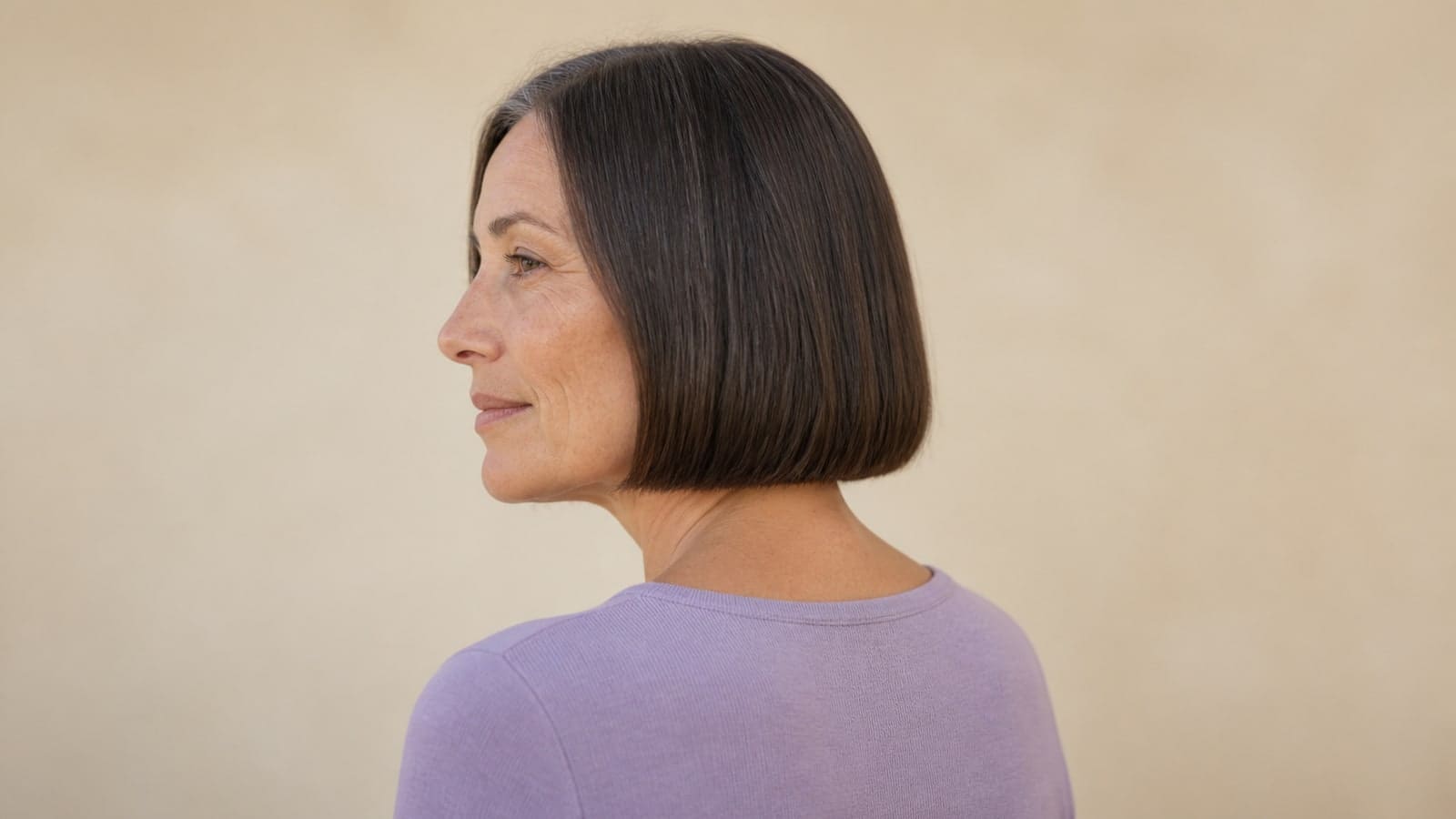 Profile view of a straight dark bob with a continuous blunt edge just below the jaw and a visible nape