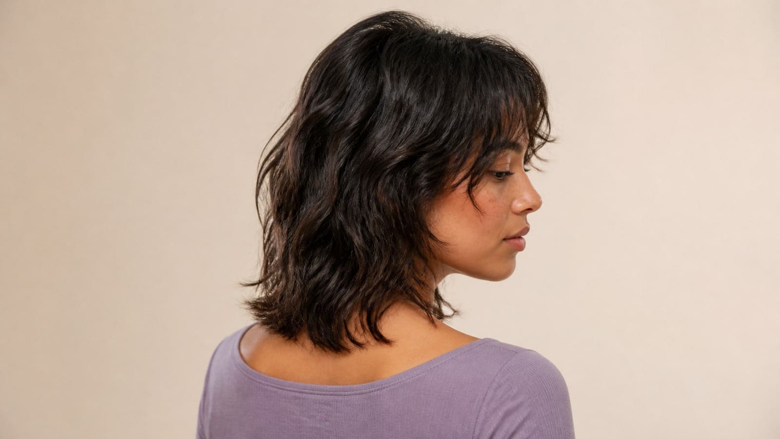 Side view of a collarbone shag with short crown layers, broken wavy ends, and a wispy fringe